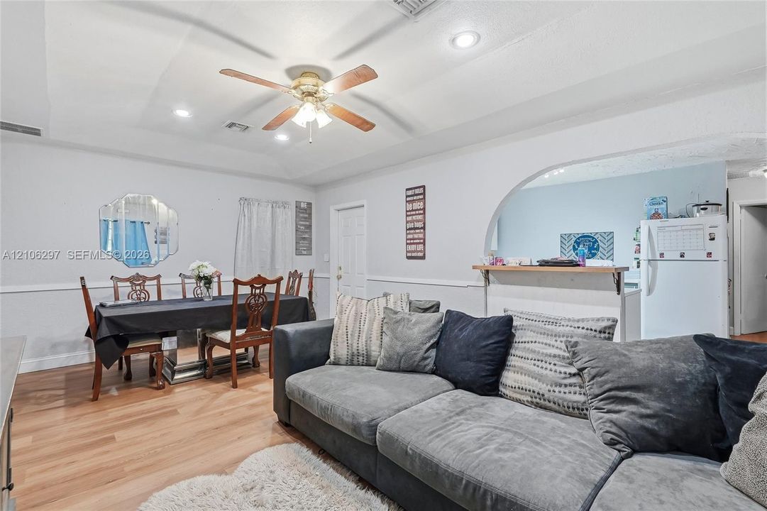 Living area featuring wood-finish flooring, recessed lighting, ceiling fan with light kit, arched wall opening, and chair rail molding
