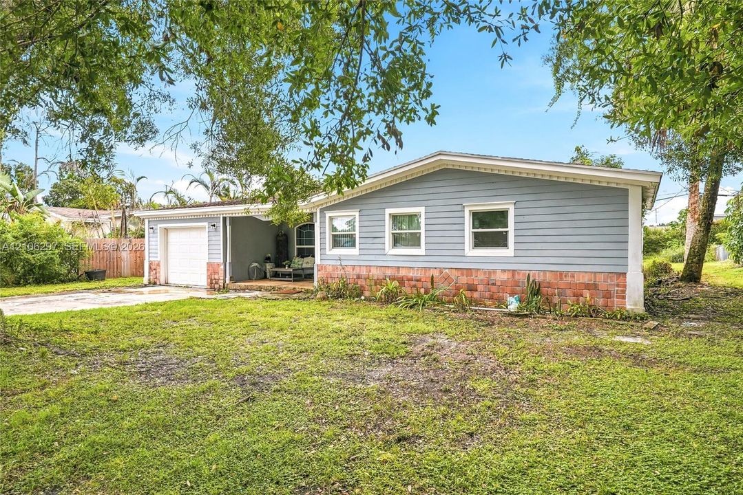 Single-story residence featuring blue horizontal siding, a red brick veneer base, a covered entryway, an attached garage, and a concrete driveway