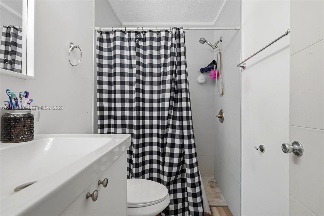 Bathroom featuring a white vanity cabinet, integrated sink, wall-mounted towel hardware, and a shower area with a handheld showerhead