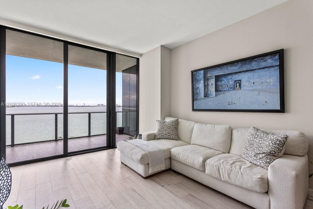 Floor-to-ceiling sliding glass doors, private balcony with metal railing, and wood-finish flooring
