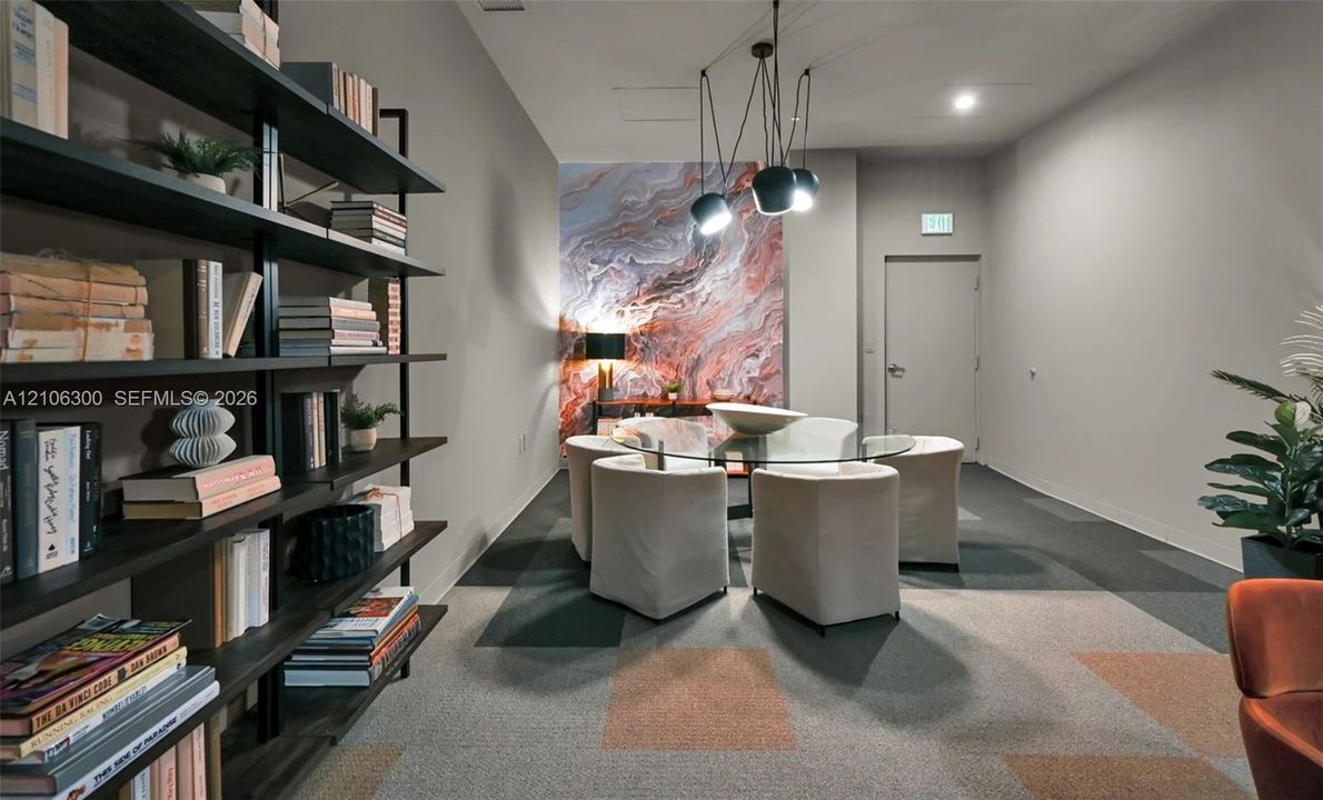 Floor-to-ceiling built-in black metal shelving unit, geometric patterned modular carpeting, decorative marble-finish accent wall, and multi-pendant modern light fixture
