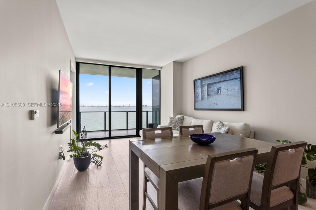 Neutral wall tones, wood-finish flooring, floor-to-ceiling glass sliding doors, and a private balcony featuring a metal railing