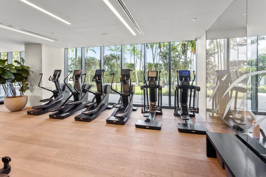 Fitness center featuring floor-to-ceiling windows, wood-finish flooring, mirrored wall, and recessed linear lighting
