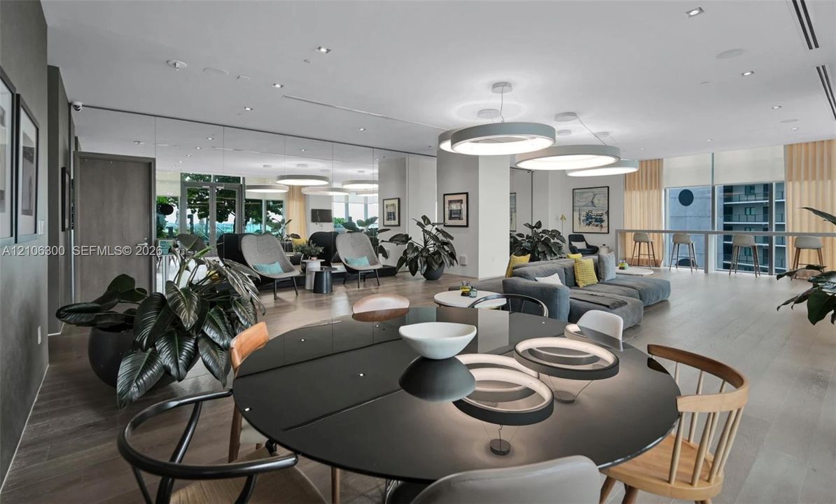 Open-concept interior featuring wood-finish flooring, recessed lighting, expansive floor-to-ceiling windows, and large circular pendant light fixtures
