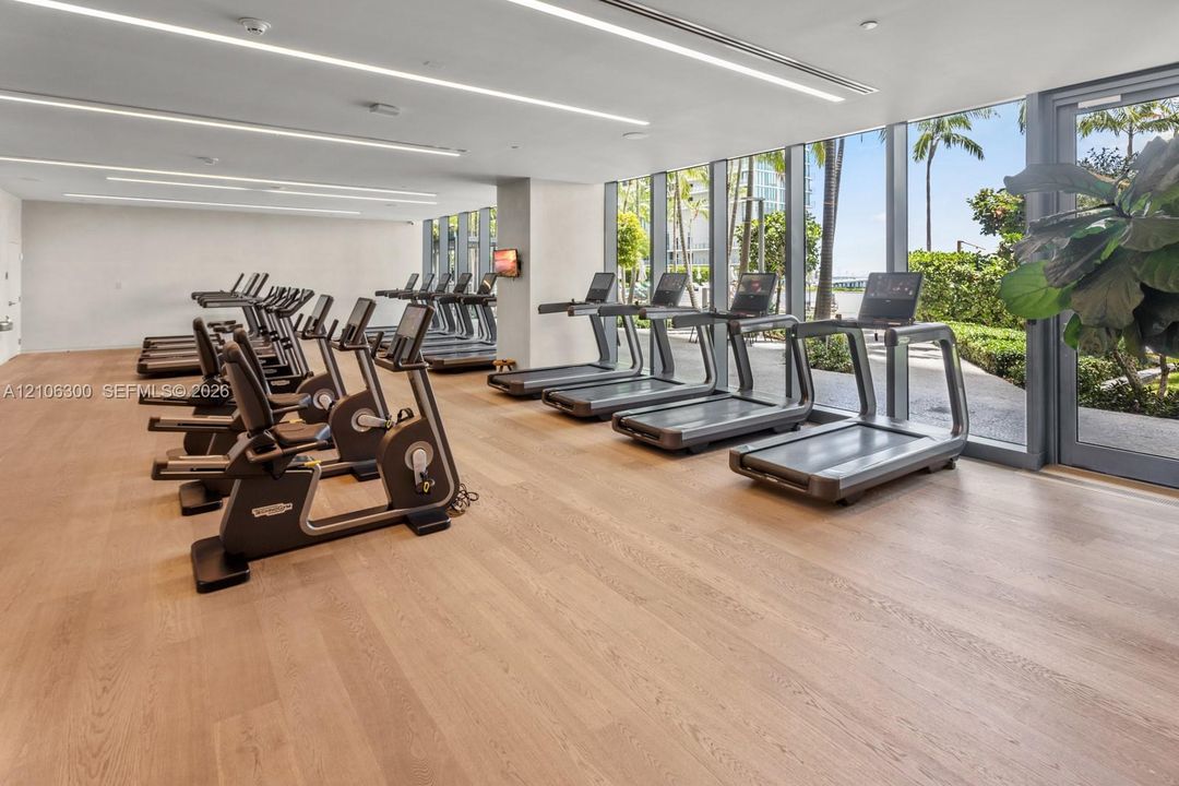 Fitness center featuring wood-finish flooring, floor-to-ceiling windows, and recessed linear lighting