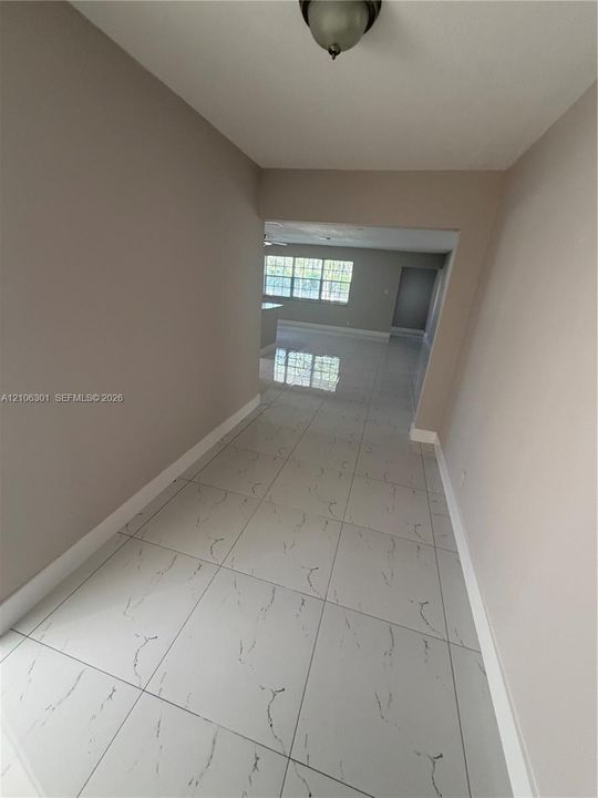 Large-format tile flooring with marble-pattern veining, neutral interior paint palette, and ceiling-mounted dome light fixture