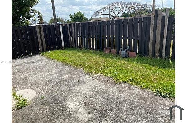 Fenced outdoor space featuring a concrete patio and lawn area