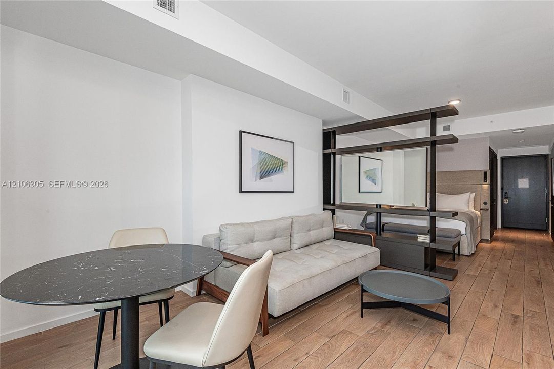 Open-concept interior featuring wood-finish flooring, a built-in dark-toned room divider, and recessed lighting