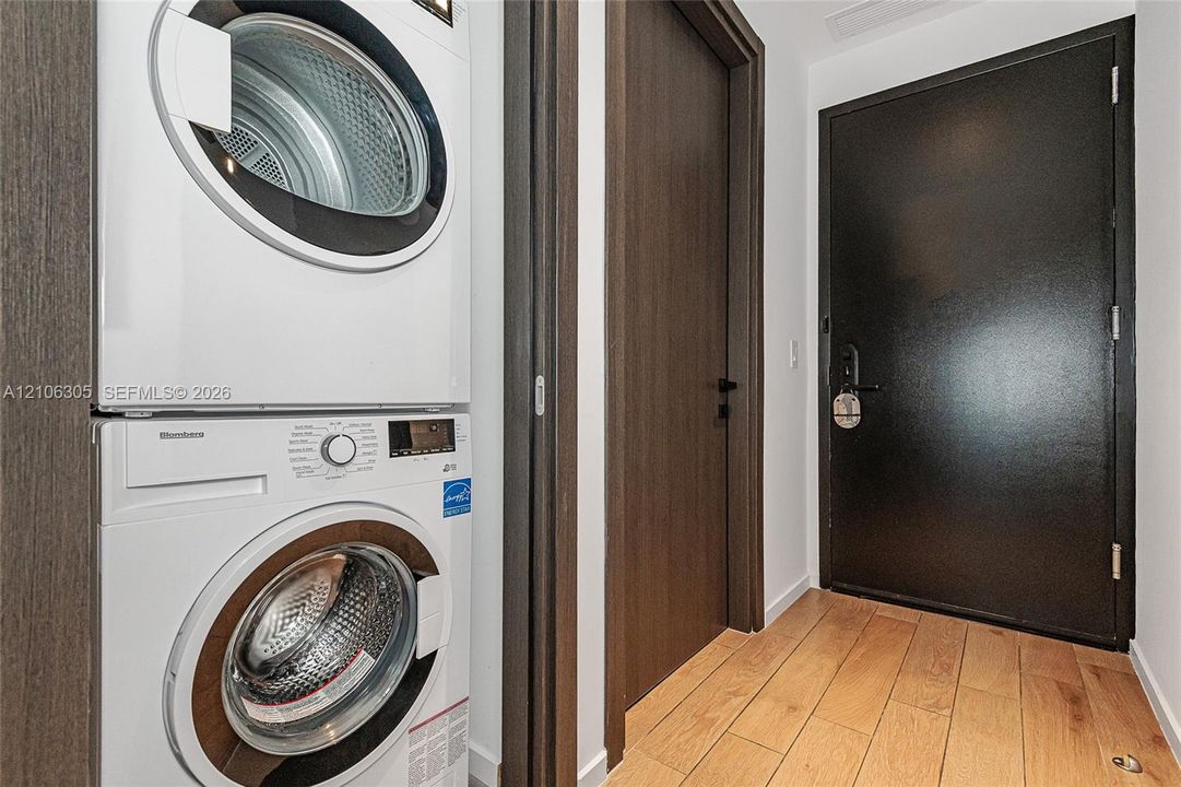 Stackable front-load laundry unit, wood-finish flooring, and solid-core dark finish interior door