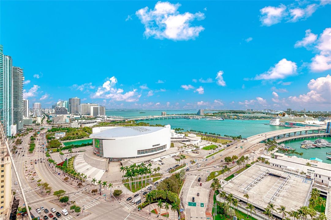 Aerial perspective showcasing an expansive urban skyline, coastal bay waters, marina infrastructure, and metropolitan thoroughfares