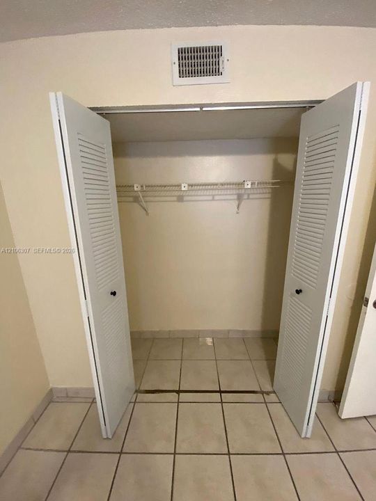 Reach-in closet featuring white louvered bifold doors and wire shelving