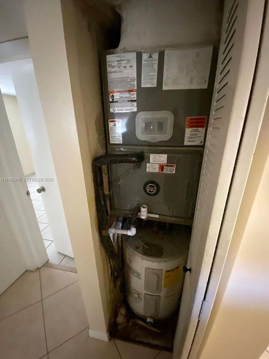 Utility closet housing a forced-air furnace unit and a cylindrical water heater