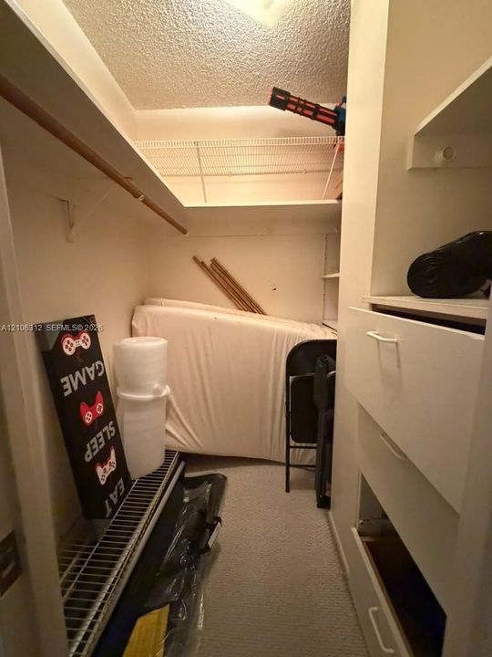 Storage area featuring built-in shelving, white integrated cabinetry with drawers, and wire rack shelving