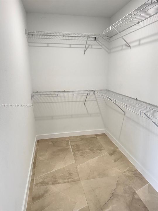 Walk-in closet featuring large-format tile flooring and tiered wire shelving