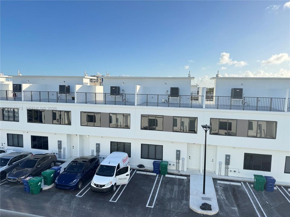Contemporary multi-story exterior featuring a crisp white finish, flat roofline, integrated rooftop balconies with metal railings, and oversized rectangular windows