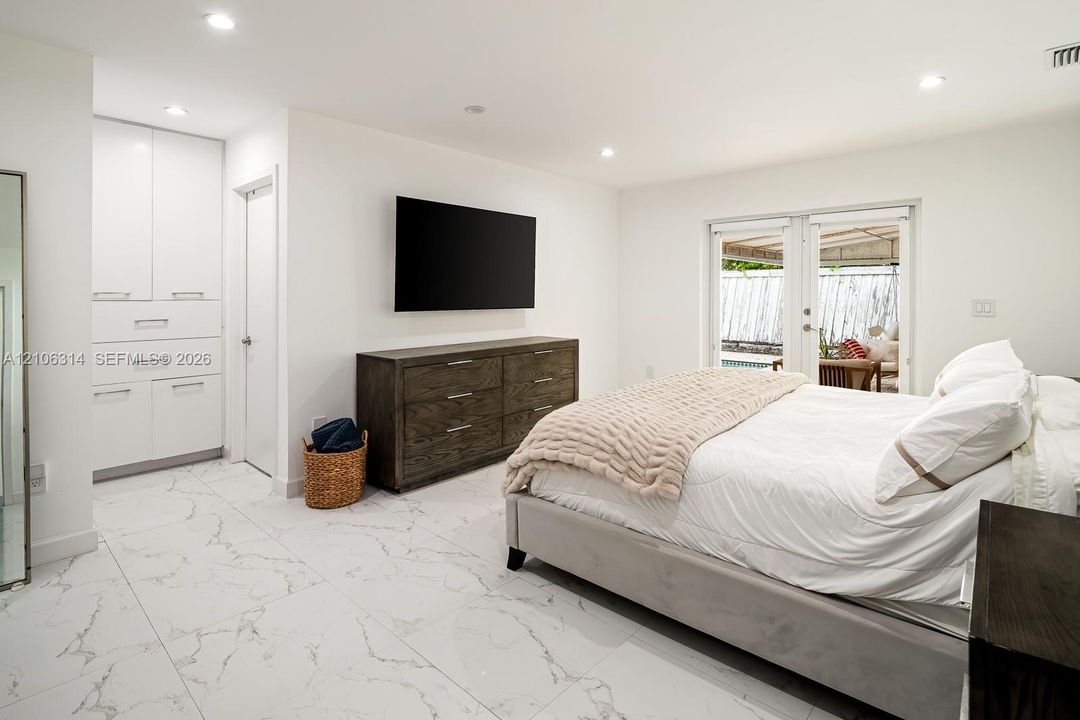 Large-format tile flooring, built-in floor-to-ceiling cabinetry, recessed lighting, and glass-paneled double doors