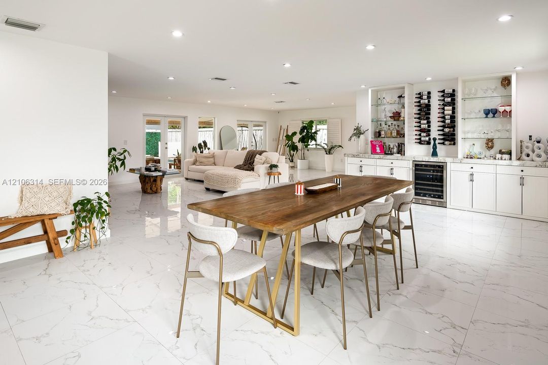 Large-format tile flooring, recessed lighting, and custom built-in cabinetry featuring integrated wine storage and glass display shelving