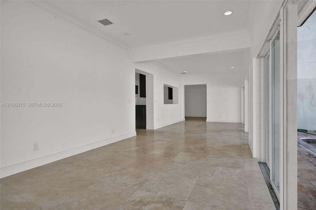 Neutral-toned large-format tile flooring, recessed ceiling lighting, and expansive multi-panel sliding glass door system
