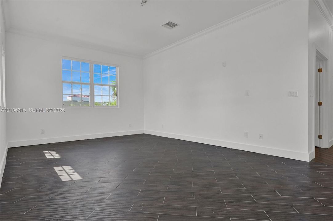 Interior room featuring wood-finish tile flooring, multi-pane window, and crown molding