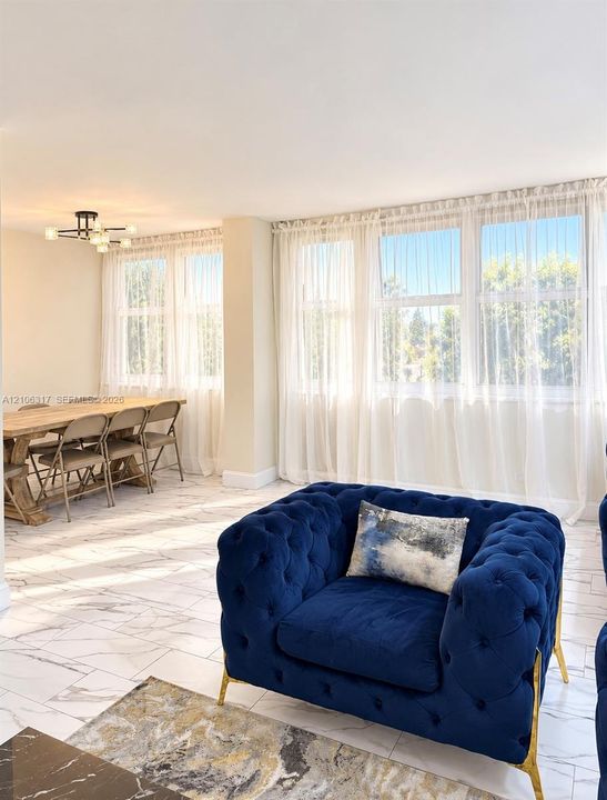 Living area featuring large windows with natural light, stone-finish flooring, and a modern multi-arm ceiling light fixture