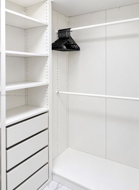 Custom closet organization system featuring adjustable white shelving, four integrated storage drawers, and dual-level hanging rods