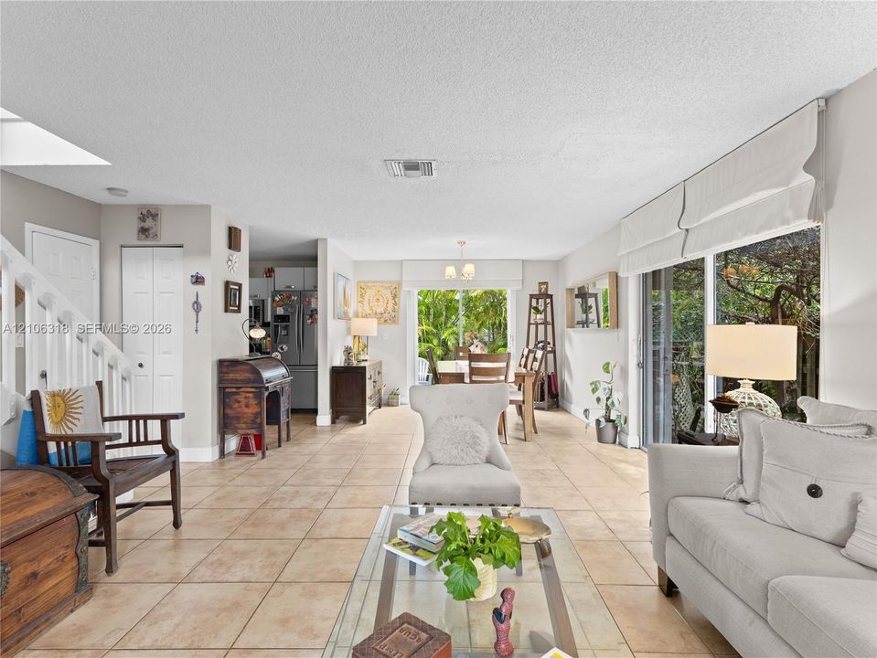 Open-concept interior featuring oversized tile flooring, sliding glass doors, built-in staircase railing, and neutral wall tones