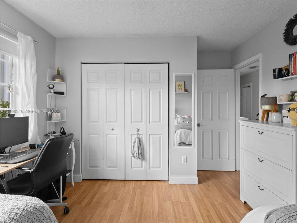 Wood-finish flooring, white paneled doors, and a wall-mounted mirror