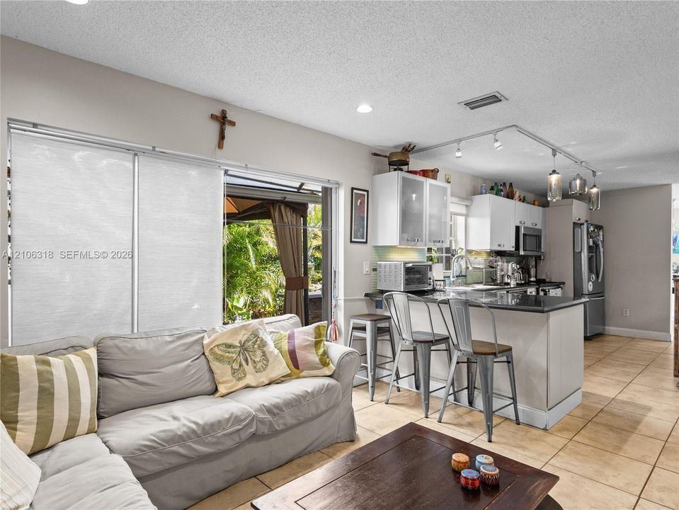 Open-concept kitchen featuring white cabinetry, a dark stone countertop peninsula, track lighting, and ceramic tile flooring