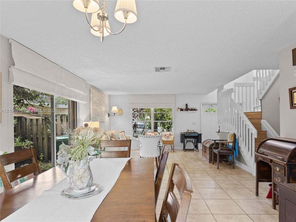 Open floor plan featuring tile flooring, multi-pane windows, sliding glass doors, a decorative chandelier.