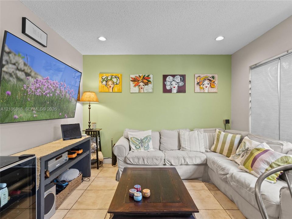 Living area featuring neutral-toned tile flooring, recessed lighting, and a green accent wall