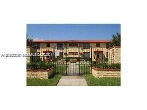 Two-story residential building exterior featuring a gated entry, stone-finished masonry pillars, and manicured landscaping