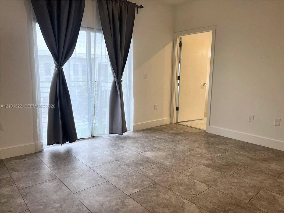 Neutral-toned large-format tile flooring and sliding glass door with exterior access