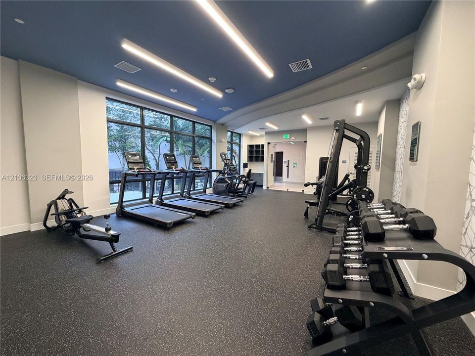 Fitness center featuring floor-to-ceiling windows, recessed and linear lighting, a blue-painted ceiling, and rubberized flooring