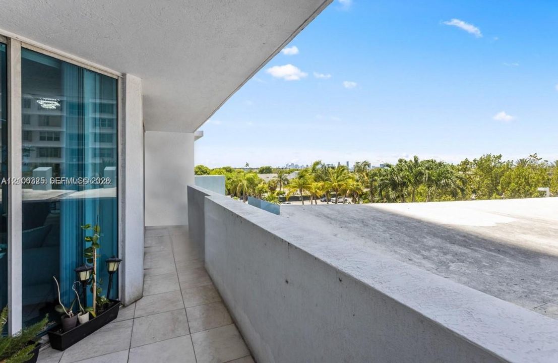Covered balcony featuring tile flooring, floor-to-ceiling glass paneling, and concrete wall accents