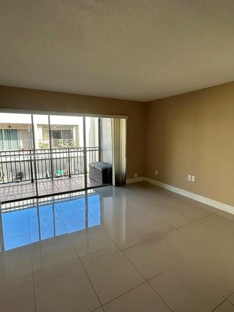 Large-format tile flooring, neutral wall tones, and floor-to-ceiling sliding glass doors opening to an exterior balcony with metal railing