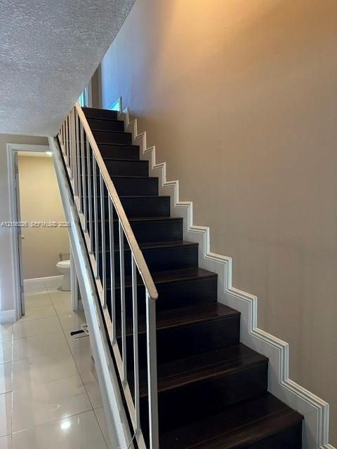 Staircase featuring dark wood-finish treads, white structural railing, and decorative wall molding