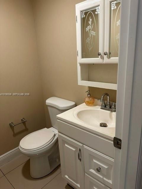 White vanity cabinet with an integrated basin, chrome-finish dual-handle faucet, and wall-mounted upper cabinet featuring etched glass door panels