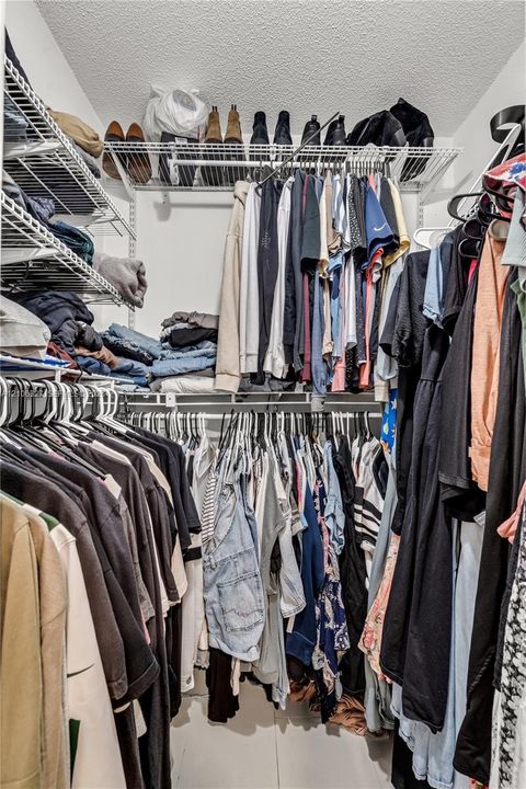 Walk-in closet featuring tiered white wire shelving and overhead storage racks