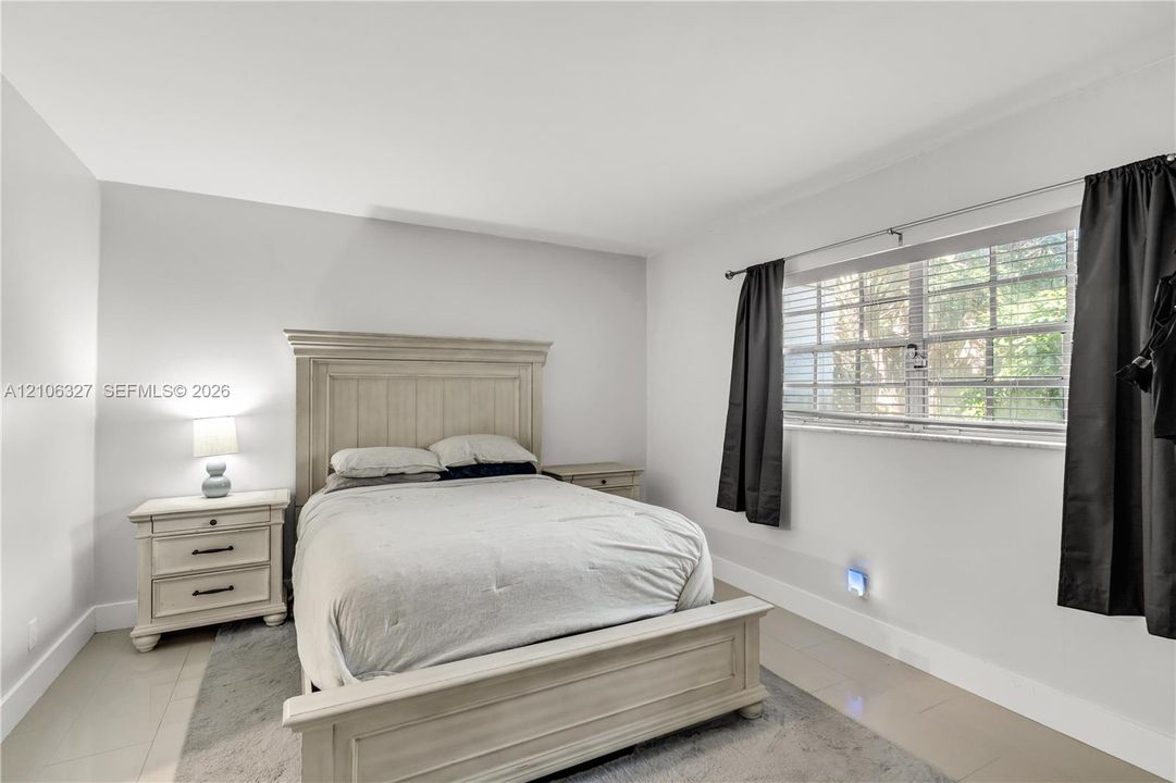Neutral-toned ceramic tile flooring, horizontal window blinds, and crisp white wall finishes
