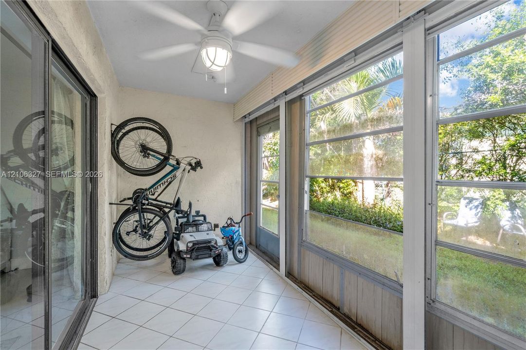 Enclosed patio featuring tile flooring, a ceiling fan with integrated lighting, and extensive window paneling