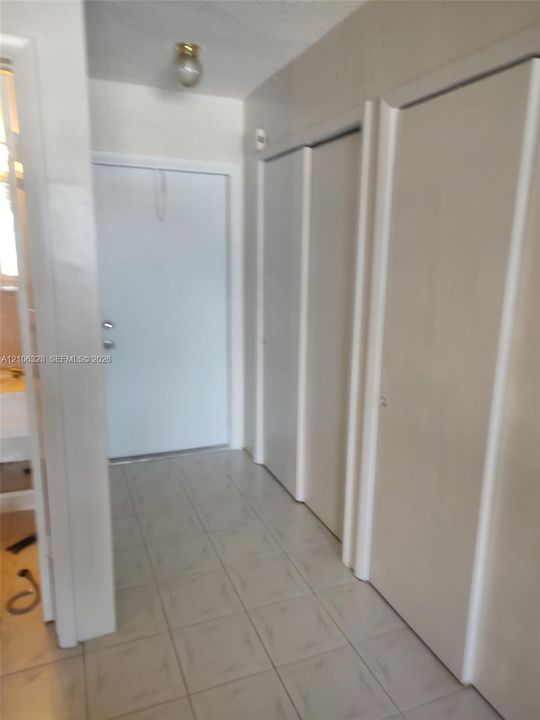 Entryway featuring light-toned tile flooring, dual-panel closet doors, and flush-mount lighting