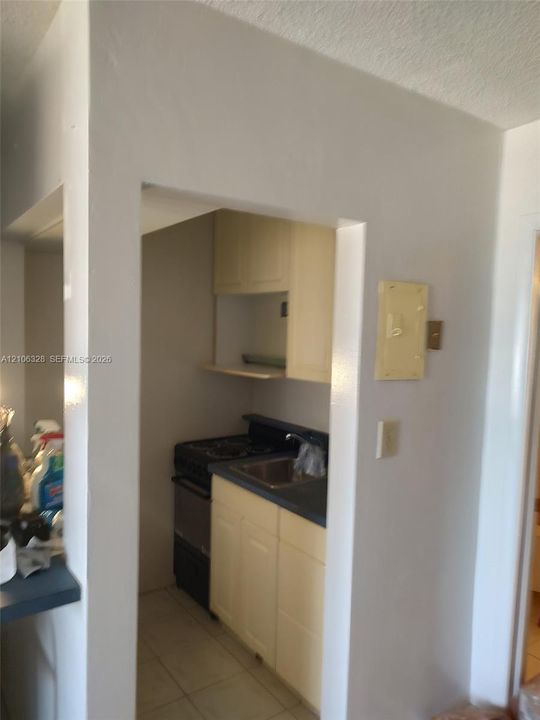 Kitchenette featuring light-finish cabinetry, built-in shelving, dark-tone countertops, and tile flooring