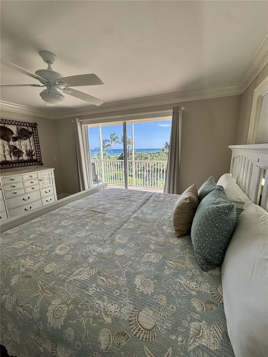 Sliding glass doors opening to a railed balcony, crown molding, and a ceiling fan