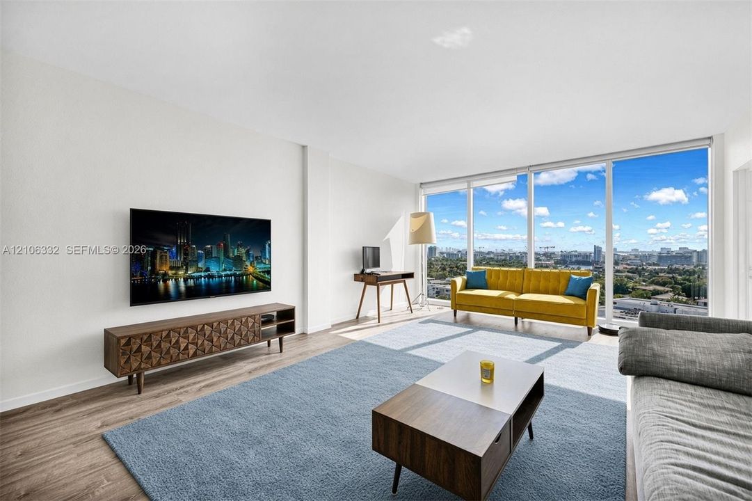 Floor-to-ceiling windows, wood-finish flooring, and expansive urban scenery
