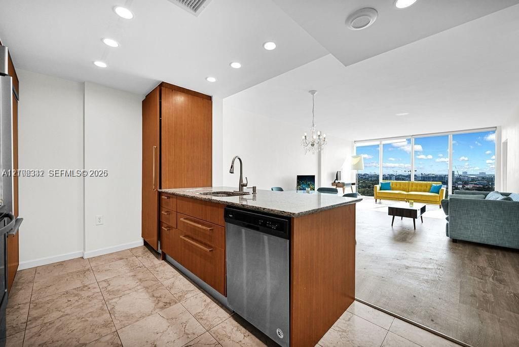 Kitchen featuring wood-finish cabinetry, stone-surface countertops, stainless steel appliances, recessed lighting, and tile flooring