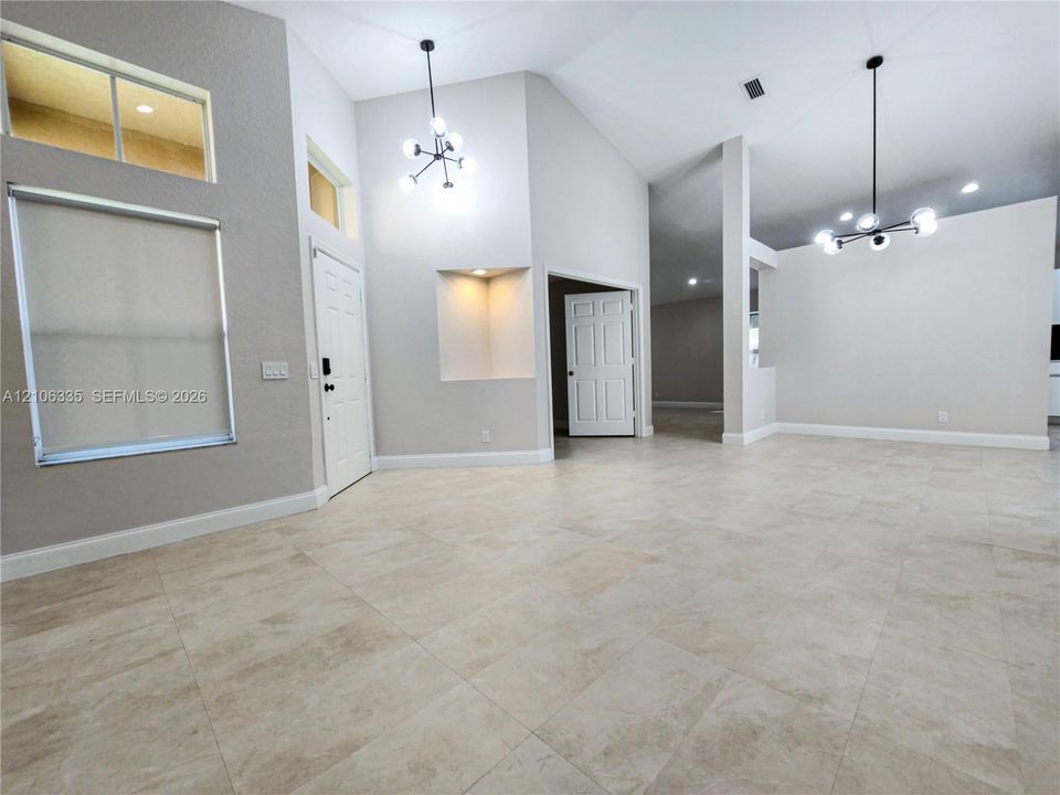 High ceilings with recessed lighting, tile flooring, multi-light chandeliers, large windows with clerestory accents, and a built-in wall niche