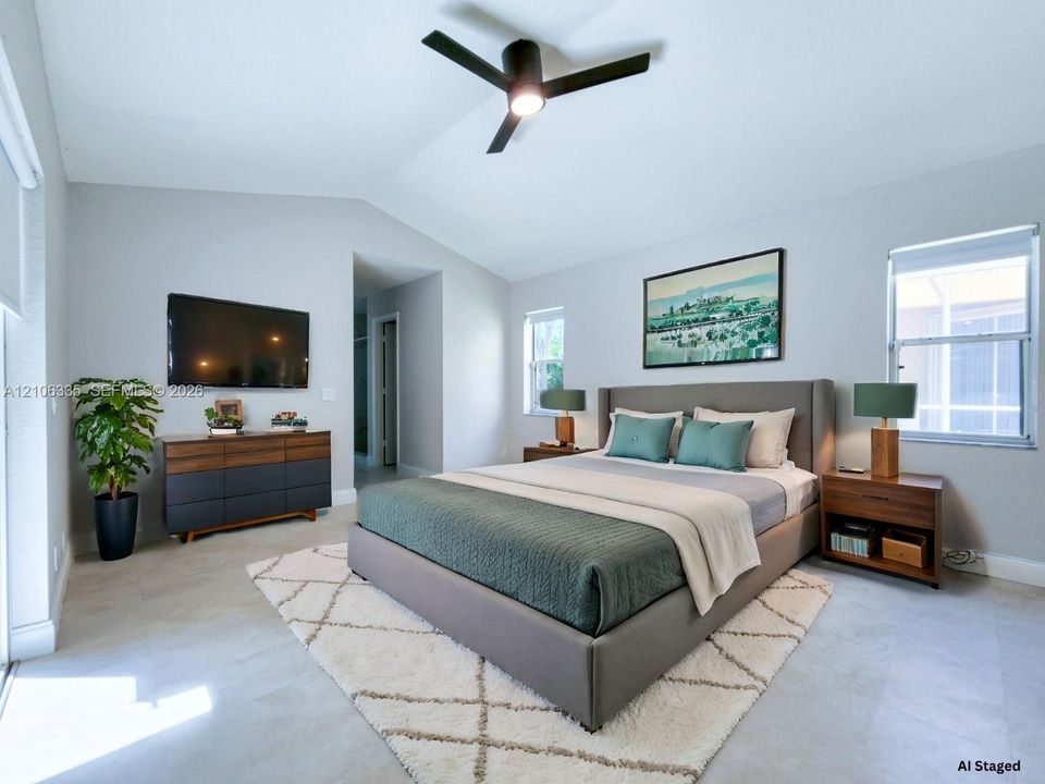Vaulted ceilings, neutral walls, light-toned tile flooring, and a modern matte black ceiling fan