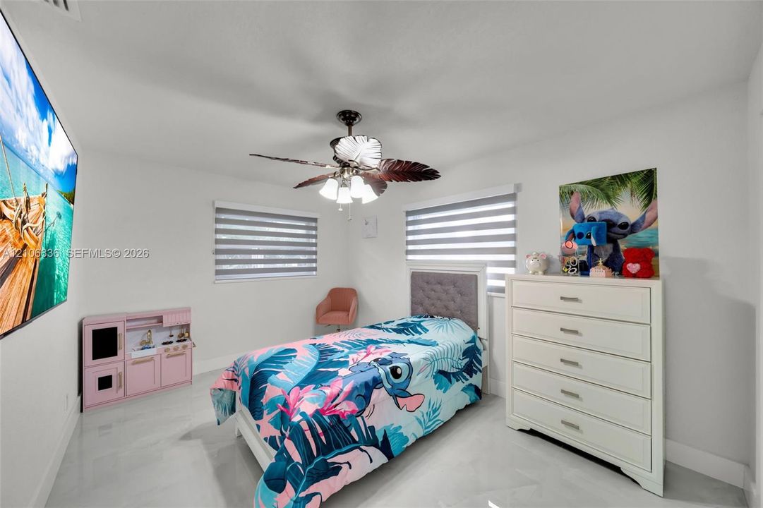 Interior space featuring large-format tile flooring, dual-tone roller shades, and a ceiling fan with integrated lighting