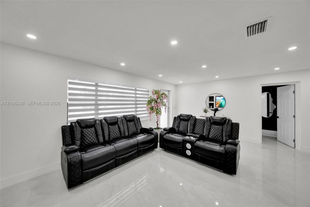 Large-format tile flooring, recessed ceiling lighting, and horizontal louvered window blinds