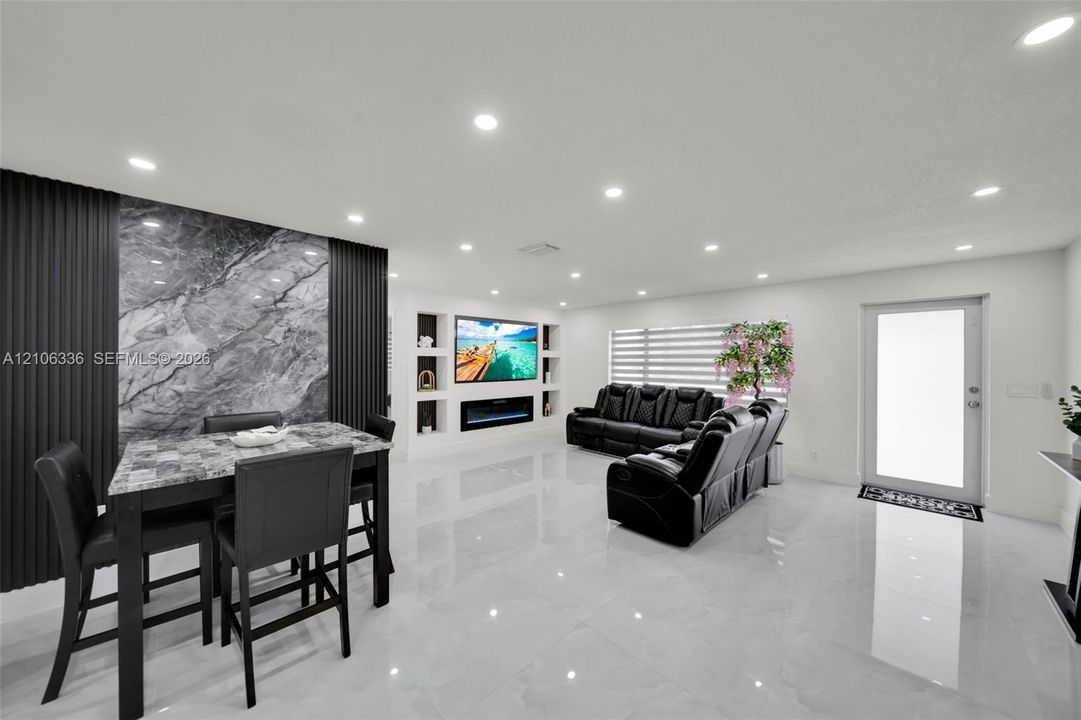 Open-concept interior featuring large-format polished tile flooring, recessed lighting, and a floor-to-ceiling stone accent wall with vertical slat detailing